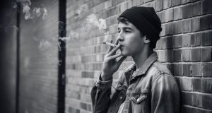 Global Tobacco Epidemic: 37 Million Children Ages 13-15 Use Tobacco, Experts Warn a-candid-black-and-white-photograph-of-a-male-teen-smiking