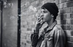 Global Tobacco Epidemic: 37 Million Children Ages 13-15 Use Tobacco, Experts Warn a-candid-black-and-white-photograph-of-a-male-teen-smiking