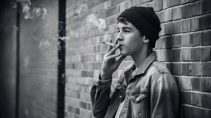 Global Tobacco Epidemic: 37 Million Children Ages 13-15 Use Tobacco, Experts Warn a-candid-black-and-white-photograph-of-a-male-teen-smiking