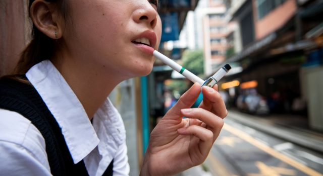 Businesses, Lawmakers Push Back Against Hong Kong’s Proposed Tobacco Control A young Asian woman smoking electronic cigarettes 002